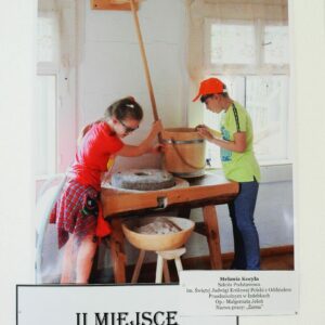 Zdjęcie przedstawia dzieci używające żarna. Zdjęcie zajęło II miejsce.