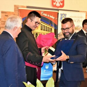 Ksiądz prałat dr Wojciech Pac otrzymuje torbę z prezentem