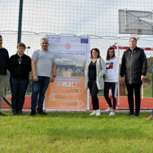 Pracownicy i studenci PANS na tle rollupu projektowego na boisku sportowympodczas wycieczki turystyczno-krajoznawcza śladami dawnej galicyjskiej linii kolejowej z Przemyśla do Budapesztu
