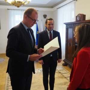 Prezydent wręcza dyplom Klaudii Biskup, w tle Rektor