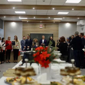 widok na salę pełną gości, na stole potrawy oraz kwiaty