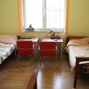 widok na pokój - dwa łóżka oraz biurka z krzesłami