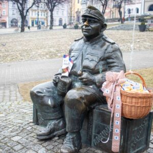 Ławeczka Józefa Szwejka w Przemyślu, obok kosz z pączkami z logo PANS w Przemyślu