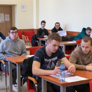 uczniowie w sali wykładowej wypełniają test