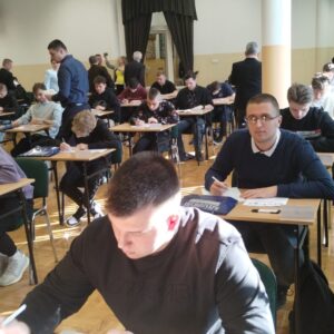 uczniowie w ławkach wypełniają test