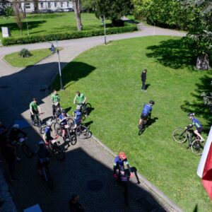 uczestnicy mistrzostw na rowerach przed Pałacem Lubomirskich, po prawej biało-czerwona flaga