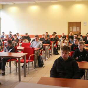 wnętrze sali dydaktycznej, uczniowie siedzą w ławkach, z przodu wykładowca PANS