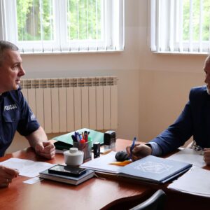 Nadkomisarz KMP oraz Kanclerz rozmawiają w gabinecie Kanclerza, siedząc przy stole