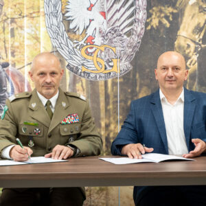 Od lewej: gen. bryg. SG Tomasz Zybiński, prof. Marek Delong przy stole, w trakcie podpisywania porozumienia