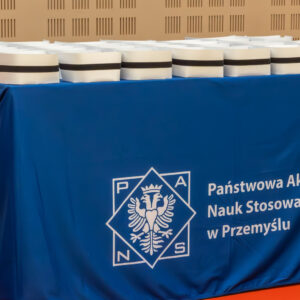 czepki pielęgniarskie ułożone na stoliku z obrusem z logo uczelni