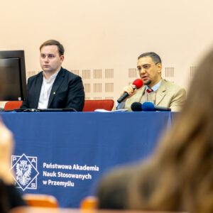 Uczestnicy panelu studenckiego przy stole konferencyjnym, głos zabiera prof. T. Olejarz