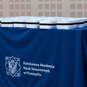 czepki na stole z obrusem z logo PANS w Przemyślu